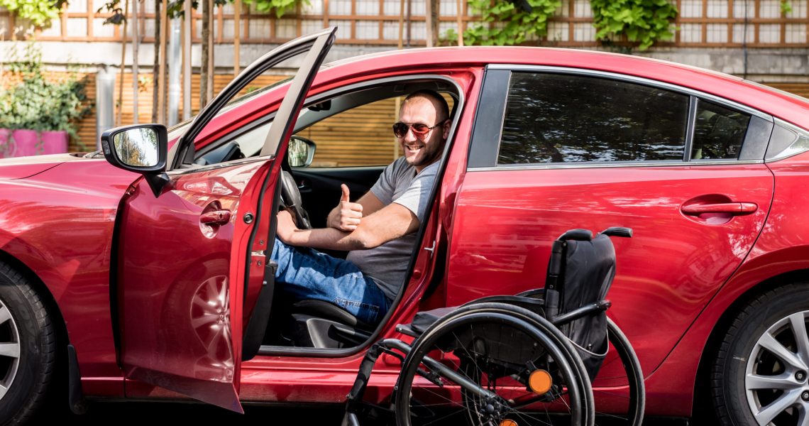 Young handicapped man on driver's seat of his car.